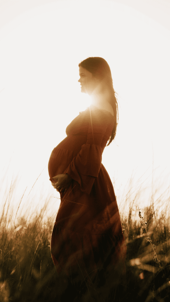 Pregnant woman with sun behind her